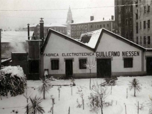 Edificio de la empresa Niessen en Errenteria (Gipuzkoa) con nieve y la torre de la iglesia parroquial de Nuestra señora de la Asunción al fondo