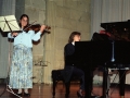 Niña tocando el violín acompañada de un piano, en Santa Ana