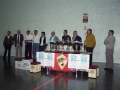 Mesa de trofeos del VII Campeonato de pelota San Miguel. Entre las personas que se encuentran junto a la pared del frontón, Eli Galdos