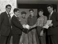 GRUPO DE HOMBRES ENTREGANDO UN PREMIO EN METALICO EN EL EXTERIOR DE UN CASERIO. (Foto 1/5)