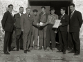 GRUPO DE HOMBRES ENTREGANDO UN PREMIO EN METALICO EN EL EXTERIOR DE UN CASERIO. (Foto 5/5)