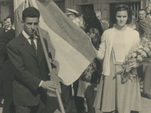 Momento del desfile en el que dos jóvenes llevan una de las banderas ganadas