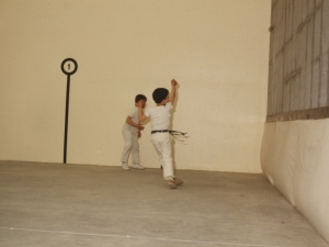 Niños jugando un partido de pelota para inaugurar el frontón cubierto