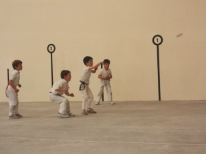 Niños jugando un partido de pelota para inaugurar el frontón cubierto