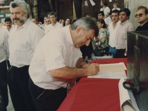 Un representante de la Cofradía de Remo firma un escrito en el que refleja la cesión por parte de dicha Cofradía al Ayuntamiento de Pasaia de un mural dedicado a los remeros y colocado en la plaza Santiago