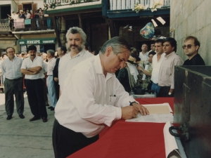 Un representante de la Cofradía de Remo firma un escrito que refleja la cesión por parte de dicha Cofradía al Ayuntamiento de Pasaia de un mural dedicado a los remeros y colocado en la plaza Santiago