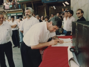 Un representante de la Cofradía de Remo firma un escrito que refleja la cesión por parte de dicha Cofradía al Ayuntamiento de Pasaia de un mural dedicado a los remeros y colocado en la plaza Santiago