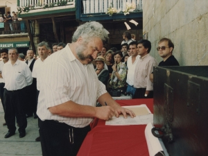 Un representante de la Cofradía de Remo firma un escrito que refleja la cesión por parte de dicha Cofradía al Ayuntamiento de Pasaia de un mural dedicado a los remeros y colocado en la plaza Santiago