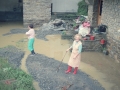 Señoras a la entrada de una casa cubierta de barro traído por el agua
