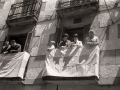 Varias mujeres y hombres contemplan el paso de la procesión del Corpus desde los balcones