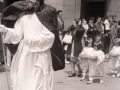 Procesión del Corpus : tras la figura de uno de los apóstoles caminan unas niñas portando cestos